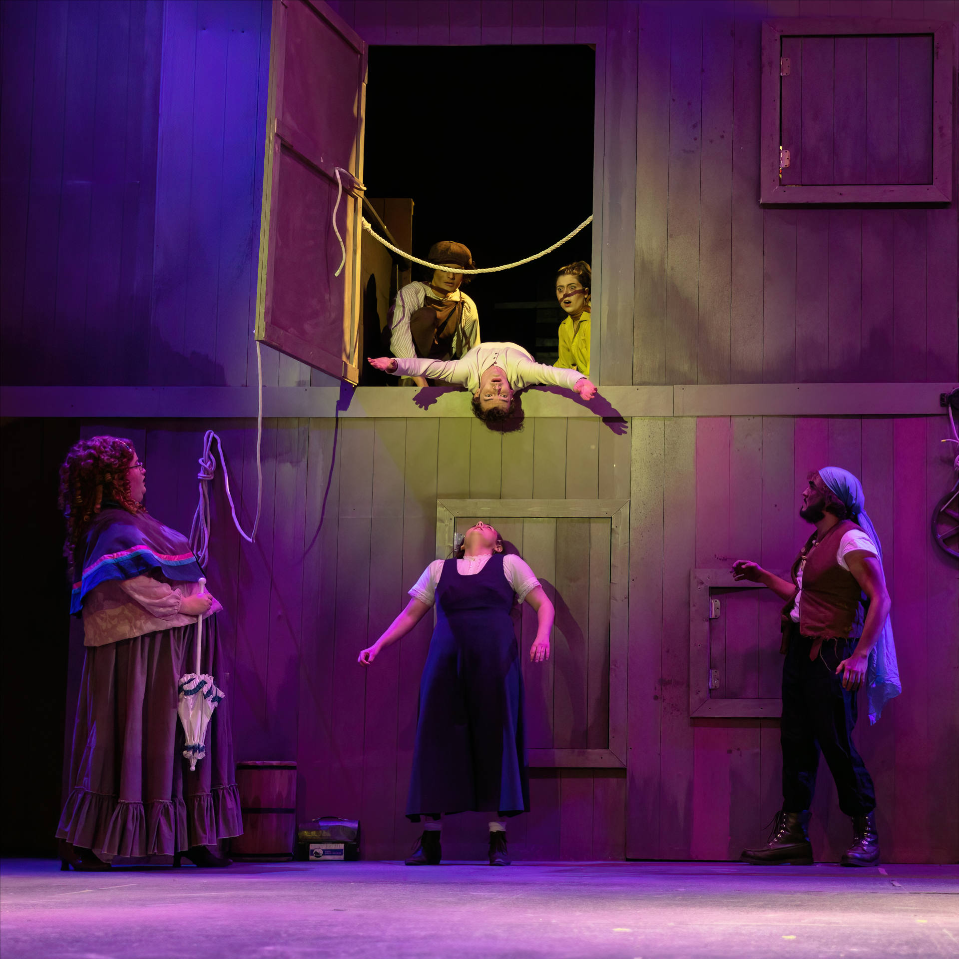 Peter Pan (Gavin Tanner) hangs outside one of the doors in the joke wall while other characters look on.
